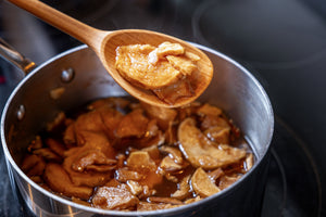 cooking spoon holding apple filling over pot