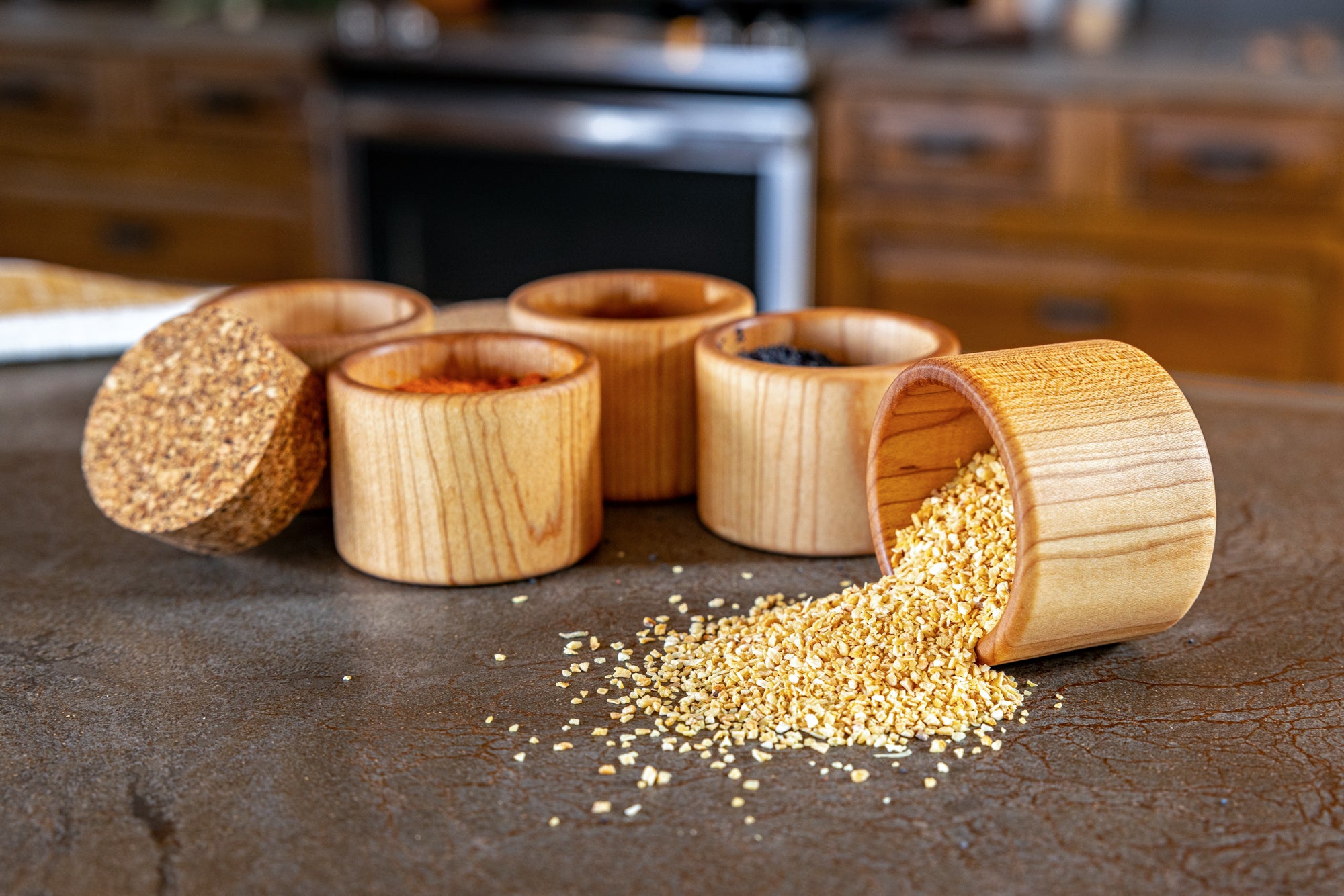 five salt cups with spices spilled on counter