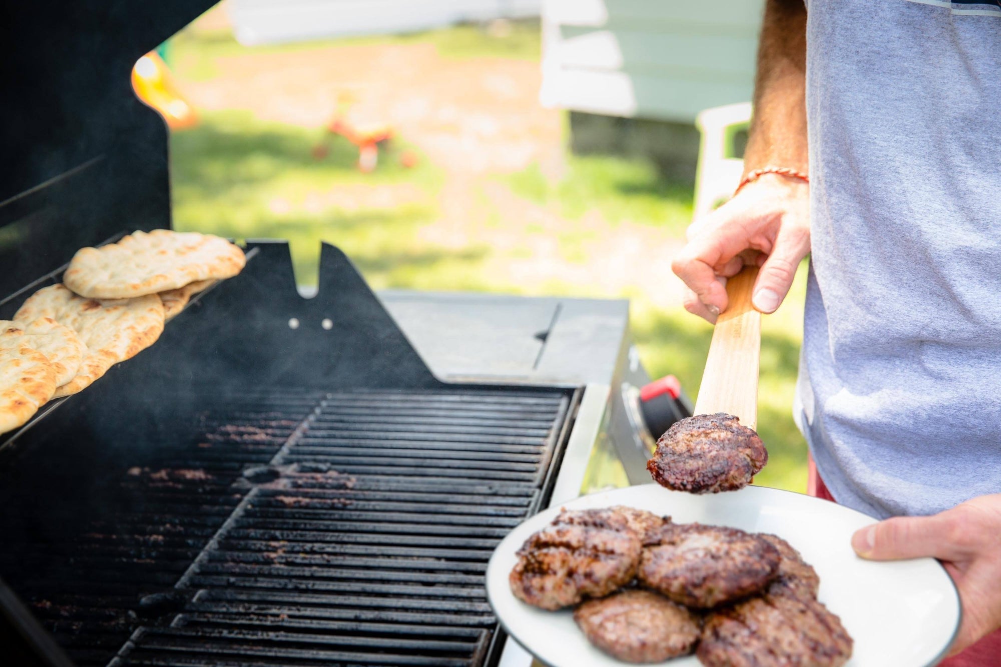 using a wood scraper spatula to cook burgers on grill - Earlywood