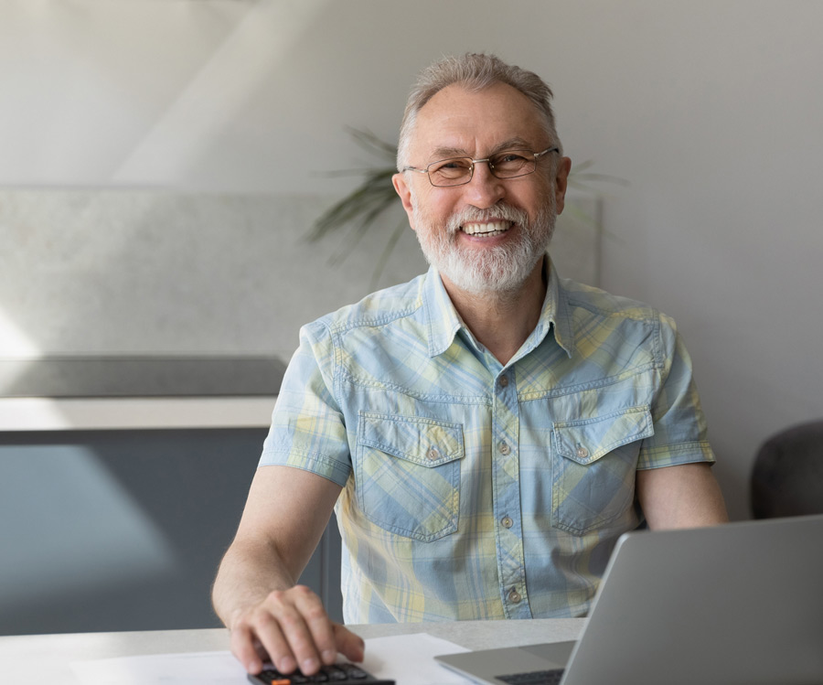 Photo of happy man sitting at a computer at his desk