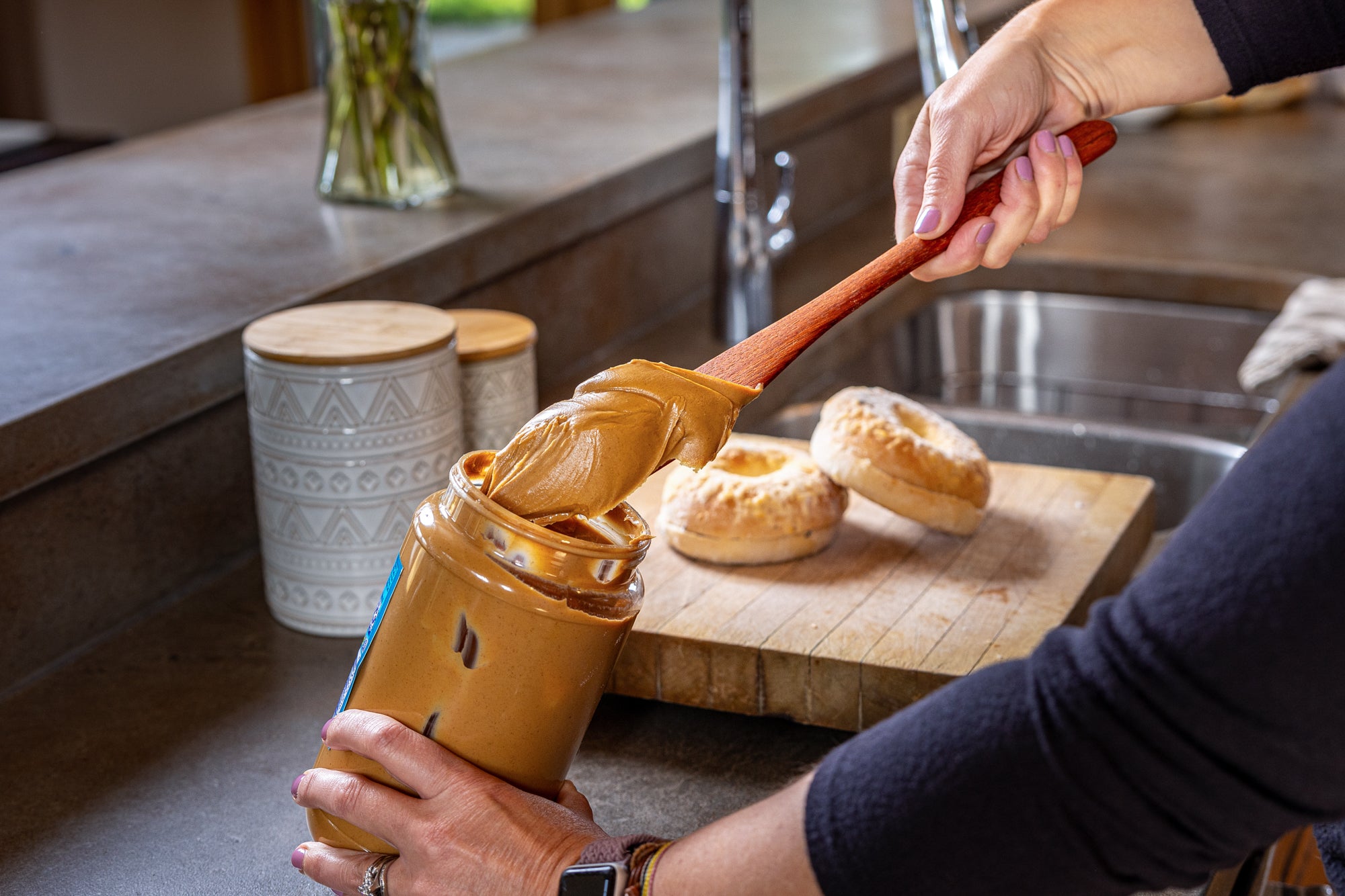 Long wooden spreader with a heaping scoop of peanut butter on the end