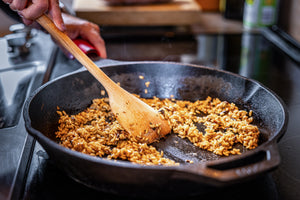 scraper spoon clearing a path of risotto in a cast iron skillet