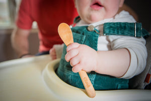 small child with personalized wooden baby spoon from Earlywood, the perfect custom baby gift