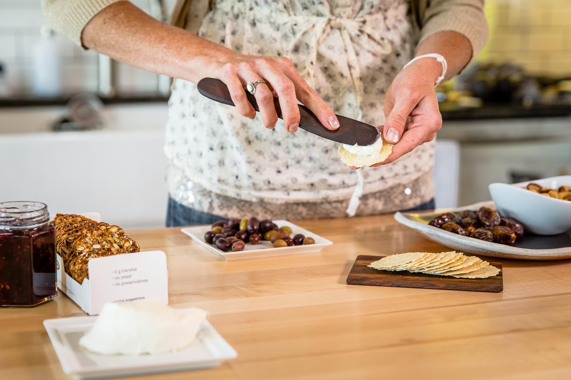 woman using wood butter spreader for soft cheese - Earlywood