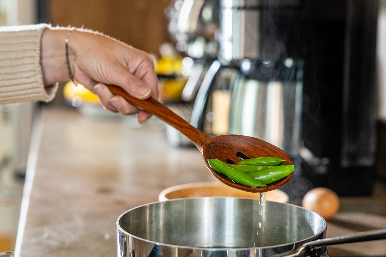 slotted wooden spoon straining peas