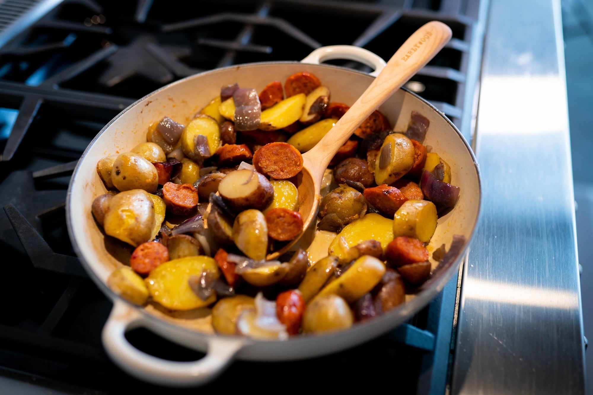 handmade wooden spoon in staub pan on stove - Earlywood